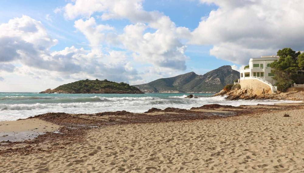 Natürlicher Sandstrand des Platja de Sant Elm auf Mallorca mit Blick auf das Mittelmeer und die Wellen.