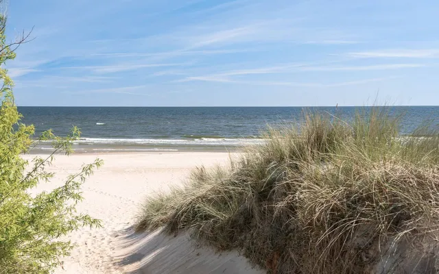 Strandaufgang durch Dünen auf Usedom, ruhiges Meer im Hintergrund.