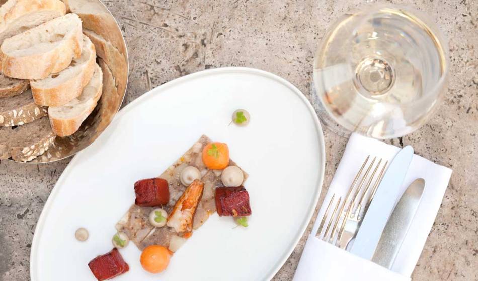 Creatively prepared fish dish with side dishes, served with bread and white wine at the Hotel Elephant Weimar.