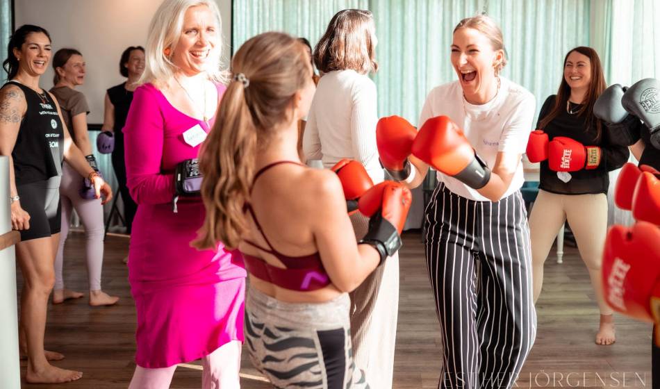 Frauen lachen und trainieren gemeinsam mit Boxhandschuhen während eines Workshops