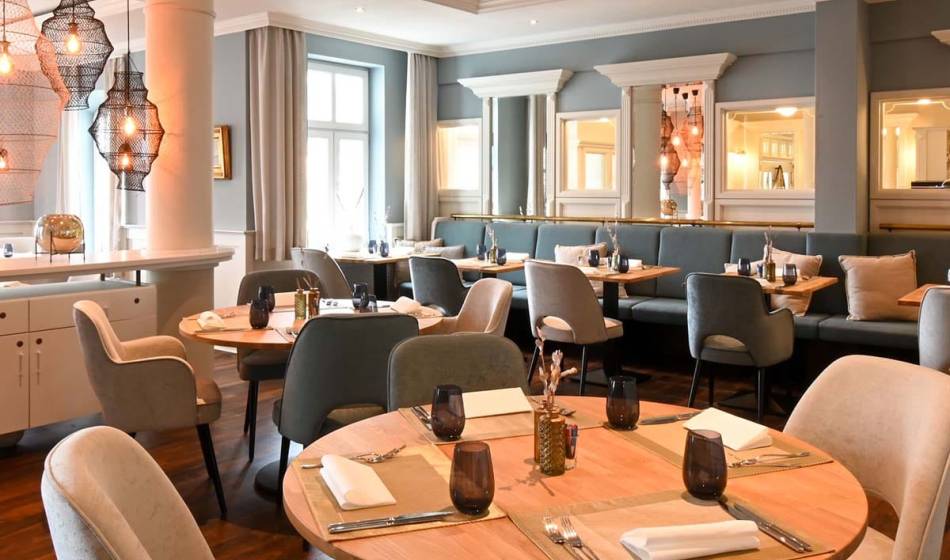Elegant Küstensilber restaurant in the Vju Hotel Rügen, furnished with set tables and stylish decor.