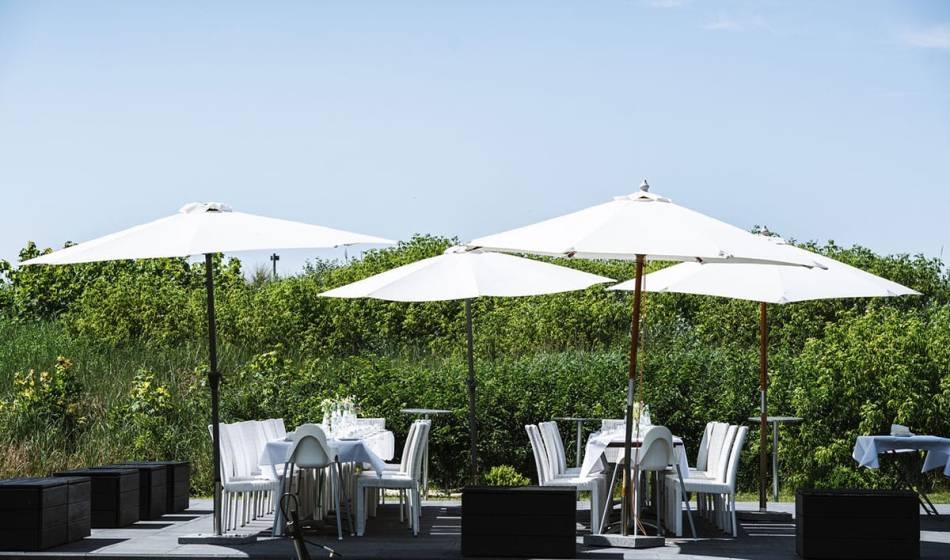 Outdoor area with wedding tables and parasols, surrounded by nature in the Hotel Künstlerquartier Seezeichen.