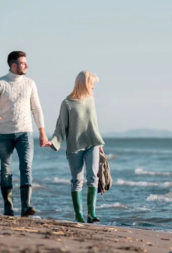 Pärchen beim Wandern am Strand mit Hund bei einem der zahlreichen Urlaubsangebote vom Vju Hotel.