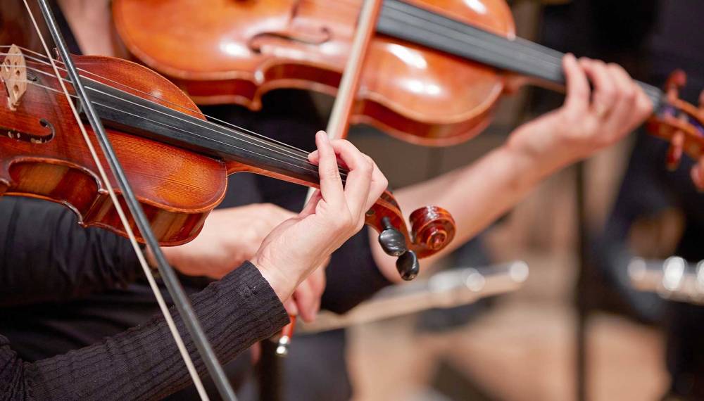 Nahaufnahme von Violinisten bei einem klassischen Konzert.