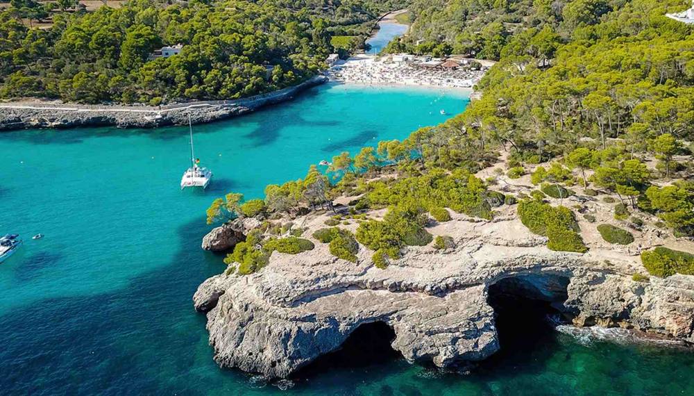Türkisblaue Bucht Cala Llombards auf Mallorca mit Felsen und klarem Wasser.