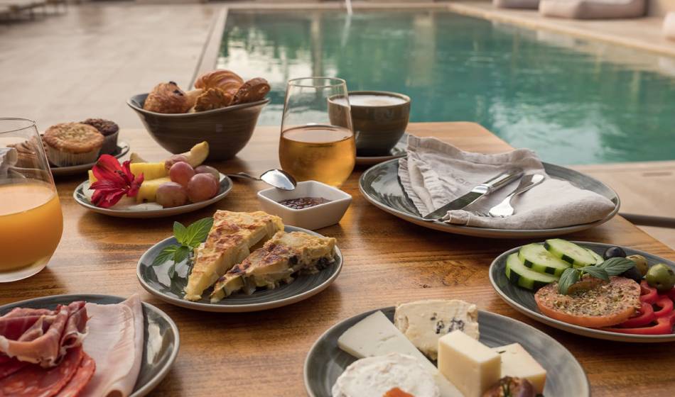 Selection of cheese, ham, fresh fruit and drinks on a poolside breakfast table at the Barefoot Hotel Mallorca.