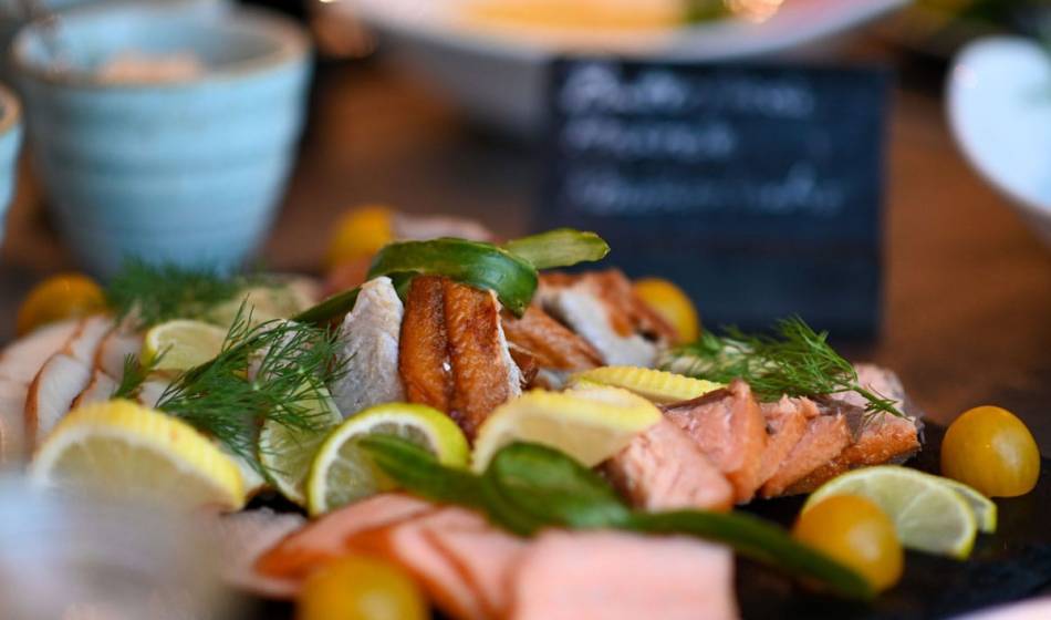 Stylishly prepared fish platter with fresh herbs, lemon and side dishes, presented at the elegant Strandläufer on Rügen.