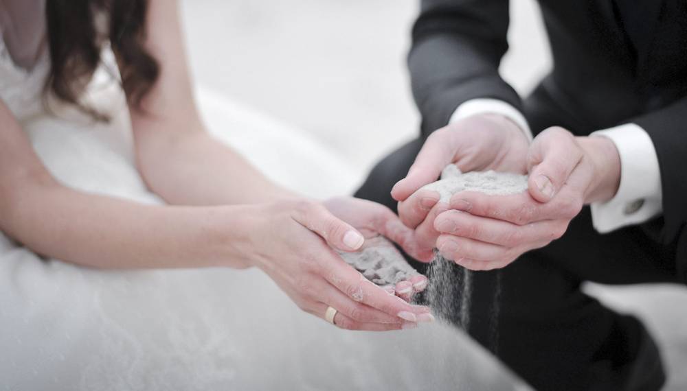 Braut und Bräutigam führen bei ihrer Hochzeit am Königsstuhl auf Rügen eine romantische Sandzeremonie durch.
