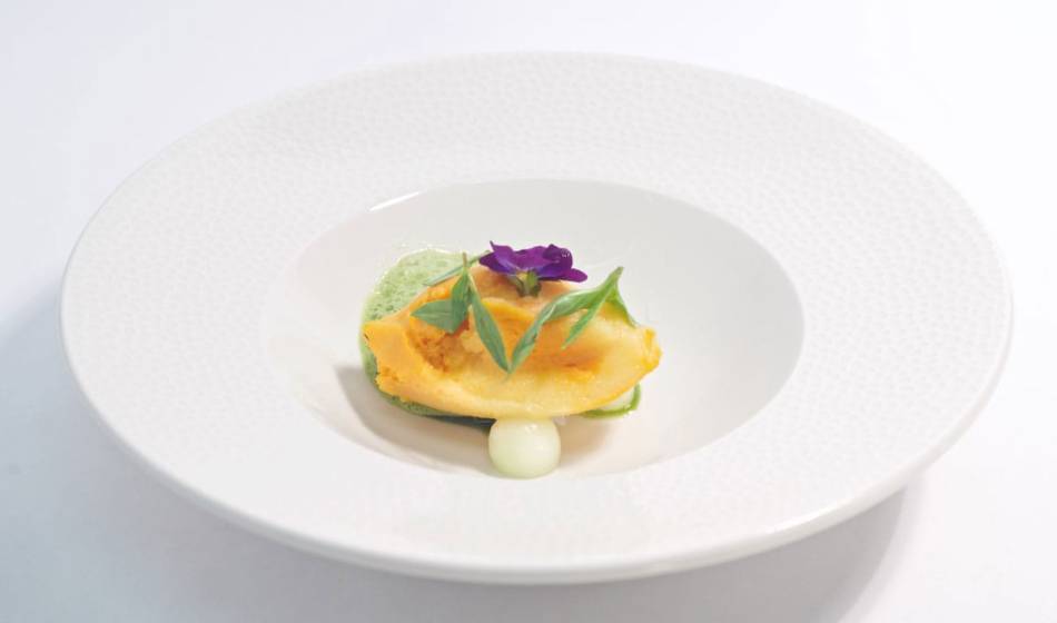Finely prepared gourmet dish in the Coastal Silver Restaurant in the Vju Hotel Rügen, with flowers and decorative vegetables.