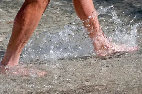 Nahaufnahme nackter Füße, die sich im kalten Wasser bewegen.