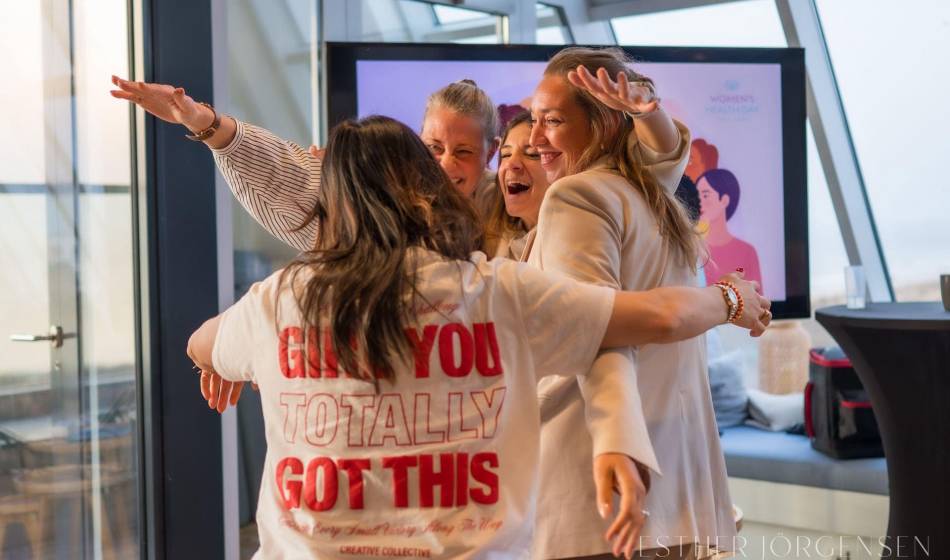 Gruppe von Frauen begrüßt sich herzlich beim Women’s Health Day in heller Eventlocation
