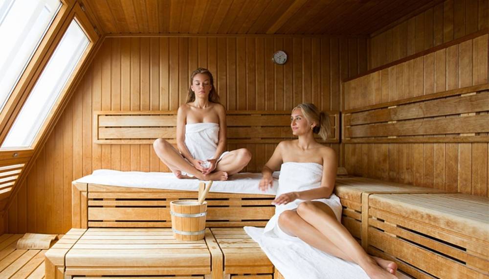 Zwei Freundinnen entspannen gemeinsam in einer Sauna und genießen eine wohltuende Auszeit.