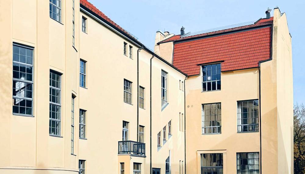 Gebäude der Bauhaus-Universität Weimar mit heller Fassade, großen Fenstern und roten Ziegeldächern.