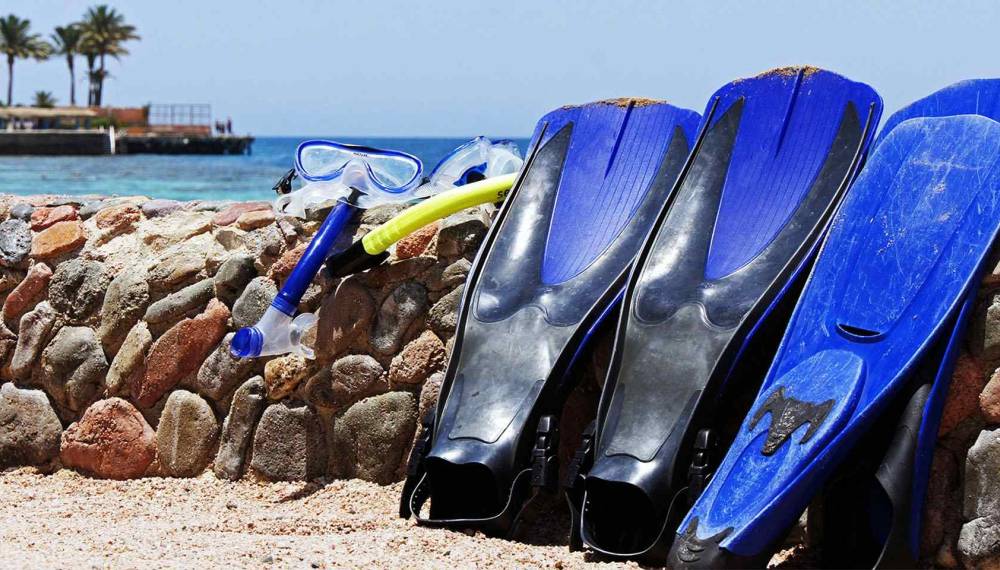 Schnorchelausrüstung mit Flossen, Maske und Schnorchel am Strand vor dem Meer auf Mallorca.