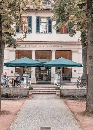 Gäste speisen auf der Terrasse vor dem Restaurant Zur Historischen Mühle in Potsdam.