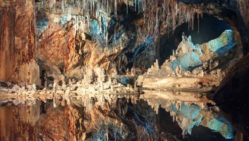Porträt der Saalfelder Feengrotten mit Stalaktiten, Stalagmiten und spiegelndem Wasser in beleuchteter Höhlenlandschaft