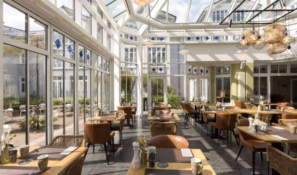 Inviting winter garden of the Strandläufer Restaurant on Rügen with elegant furnishings, a glass roof and a bright ambience.
