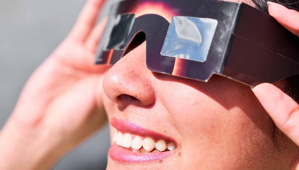 Frau mit Sonnenfinsternisbrille schaut sich eine Sonnenfinsternis auf Mallorca an. © Adobe Stock, Fabián Montaño