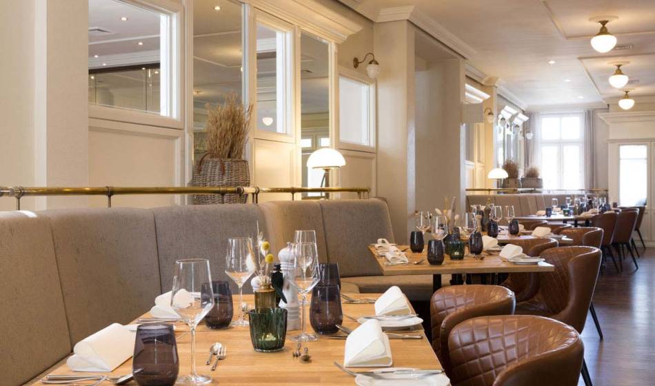 View of the Strandläufer restaurant with elegantly set tables, stylish glasses and comfortable seating.
