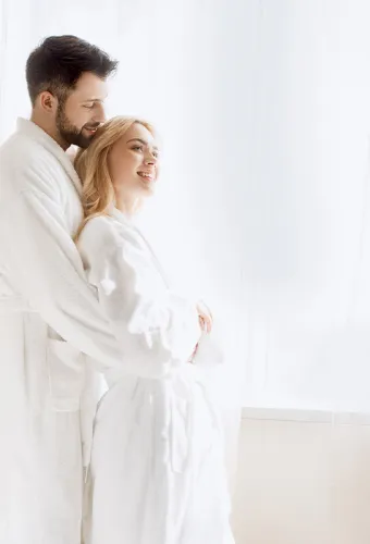 Ein Paar steht in weißen Bademänteln im Wellnessbereich des Vju Hotel Rügen.