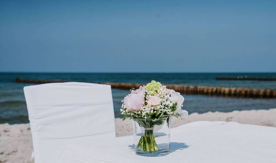 Elegant bouquet of flowers on a white table in front of the sea for a beach wedding on the Baltic Sea.