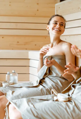 Zwei Frauen in der Sauna genießen ihre Wellness-Auszeit mit einem Lächeln im Urlaub im Vju Hotel auf Rügen.