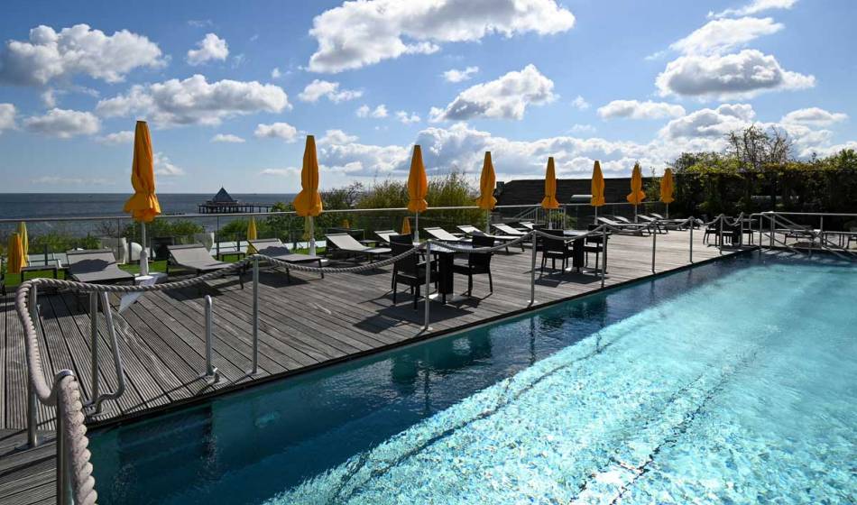 Pool terrace in the sun garden of the Hotel Kaiserhof Heringsdorf with sea views, loungers and parasols.
