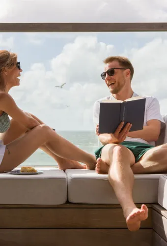 Ein Paar genießt entspannte Momente auf einer Terrasse mit Meerblick im Wyn. Strandhotel mit dem Angebot Wynsch Zweisamkeit.