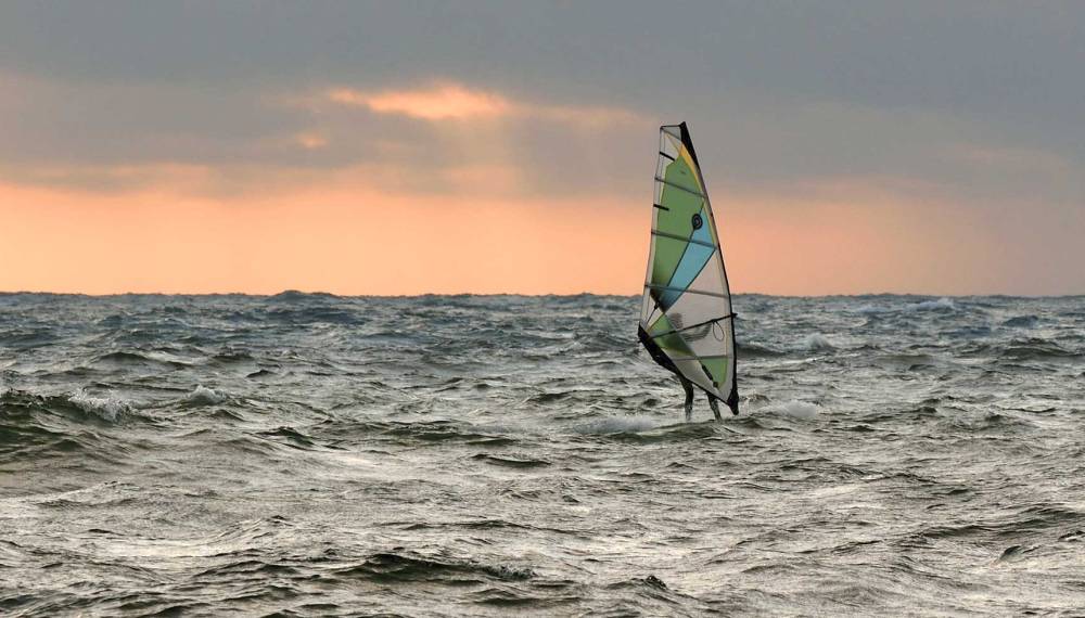 Surfer in den hohen Wellen der Nordsee vor Westerland auf Sylt bei windigem Wetter