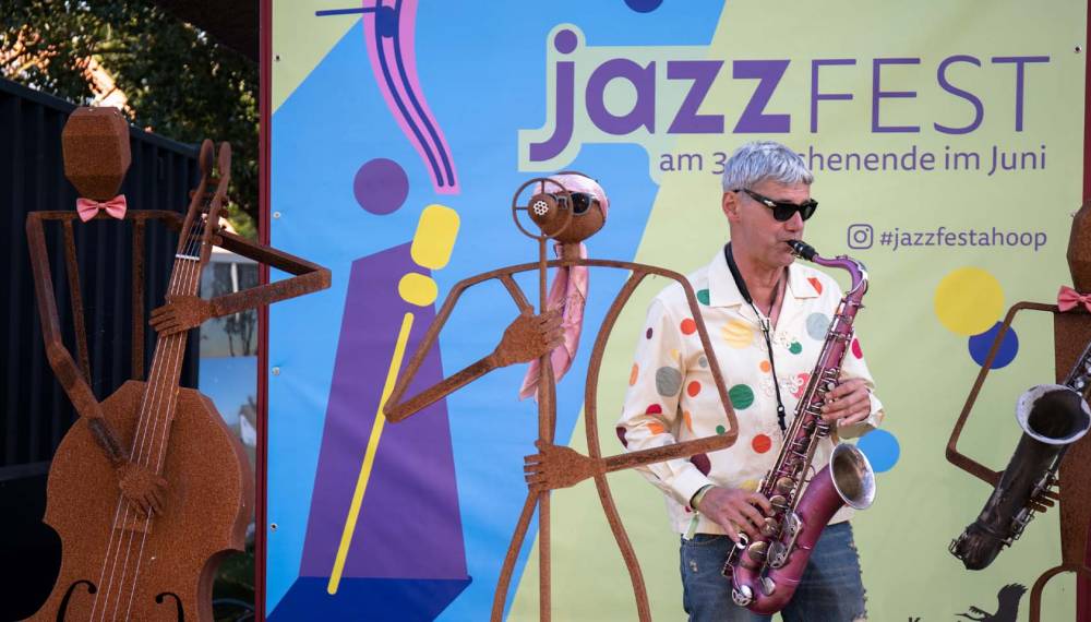Ein Musiker spielt auf seinem Saxofon vor einem Plakat des Jazzfest Ahrenshoop.