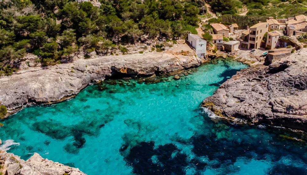 Blick auf die Bucht Cala S Almunia auf Mallorca umgeben von türkisem Wasser und Naturfelsen.