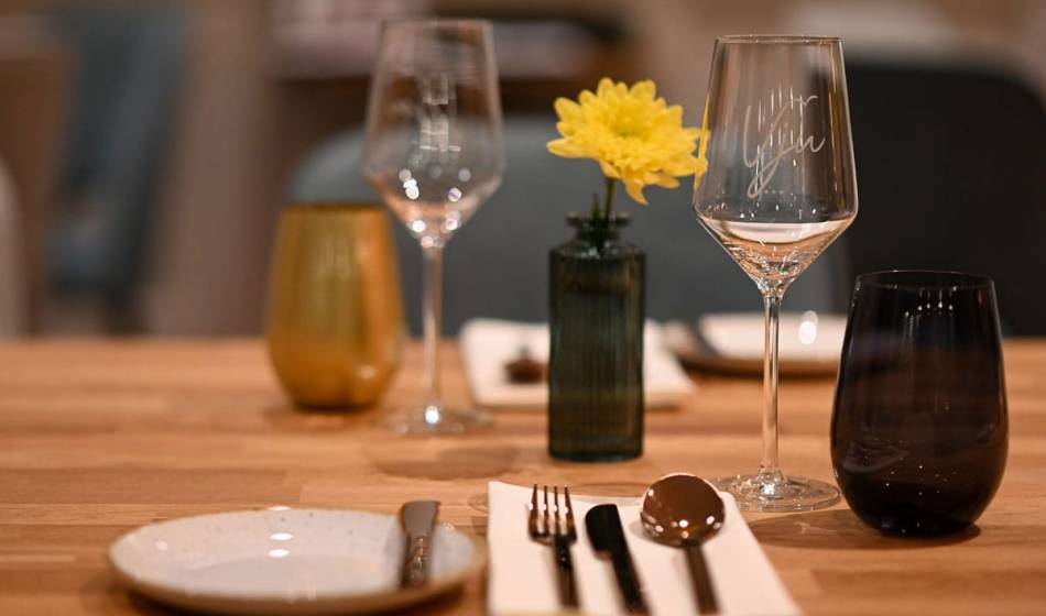 Detailed shot of an elegantly decorated table in the restaurant of the Vju Hotel on Rügen with glasses and yellow flowers.