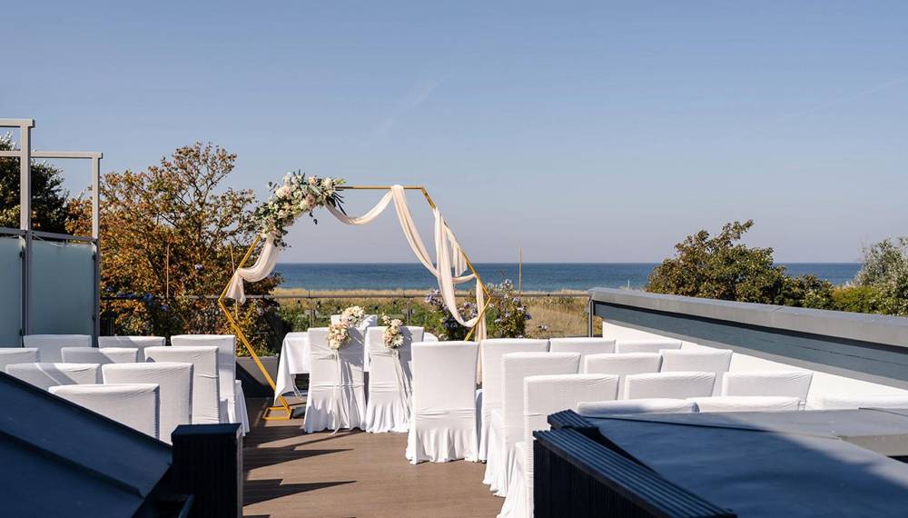 Hochzeitslocation des Hotel Künstlerquartier Seezeichen in Ahrenshoop mit Trauplatz und Blick auf die Ostsee. © sarahwenzelfotografie