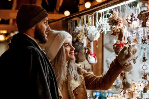 Pärchen schaut sich gemeinsam Kunsthandwerk auf dem Weihnachtsmarkt in Thüringen an.