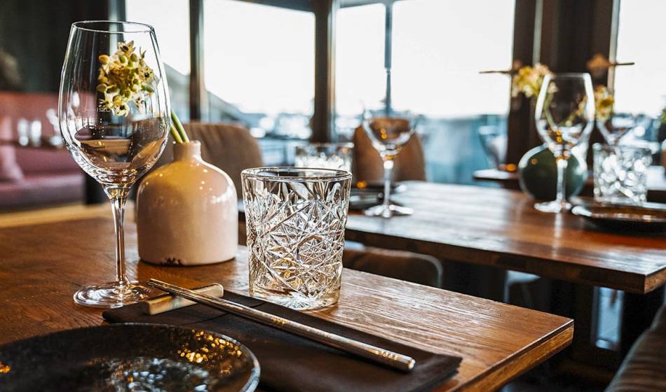 Set wooden table with wine glass, water glass and vase with flowers in the rustic interior of the restaurant #herrhoshi.