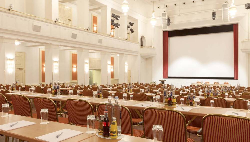 Kaiserbädersaal in Heringsdorf mit parlamentarischer Bestuhlung, langen Tischen, Getränken und großer Bühne.