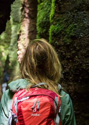 Porträt vom schattigen Schluchtenpfad durch die Drachenschlucht mit moosigen Felsen und Wanderin mit rotem Rucksack