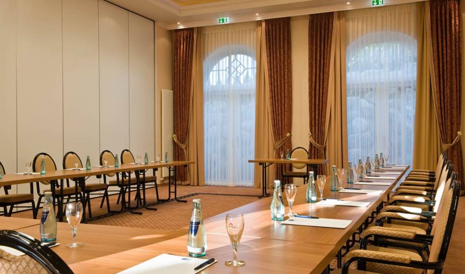 Spacious meeting room in the Vju Hotel on Rügen, with long tables, comfortable chairs and conference equipment.