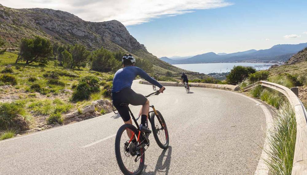 Radfahrer erkunden die Straßen Mallorcas und genießen dabei die wunderschöne Natur der Insel.