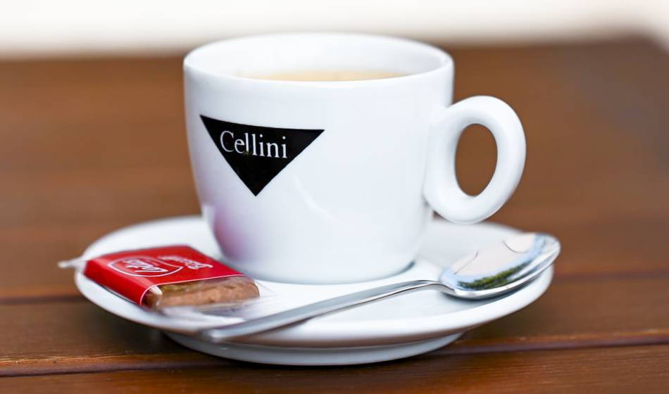 White Cellini espresso cup with spoon and biscuit on a saucer, on wooden table in cafe #fraukorn.