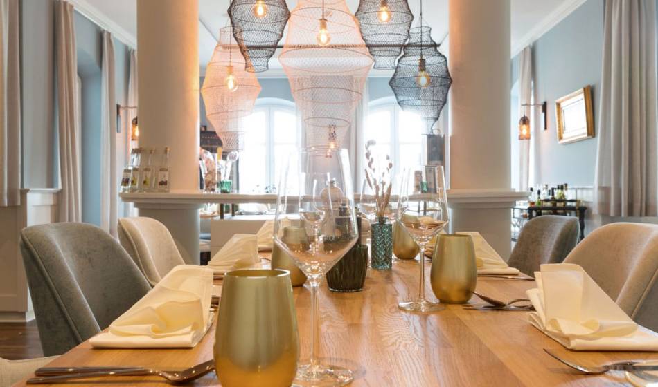 Invitingly set table in the restaurant at the Vju Hotel on Rügen with stylish glasses, napkins and elegant lighting.
