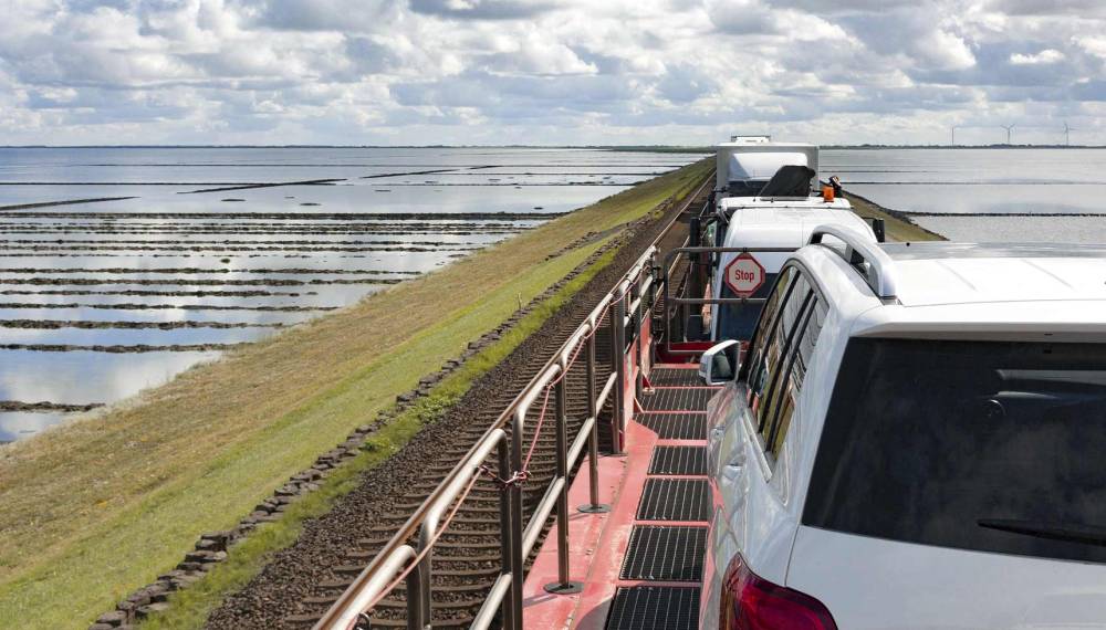 Autozug überquert den Hindenburgdamm durch das Wattenmeer auf dem Weg nach Sylt