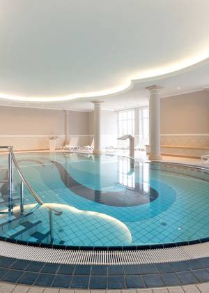 Moderner Spa-Pool im Vju Hotel Rügen mit blauer Fliesenoptik, geschwungenem Einstieg und entspannter Atmosphäre
