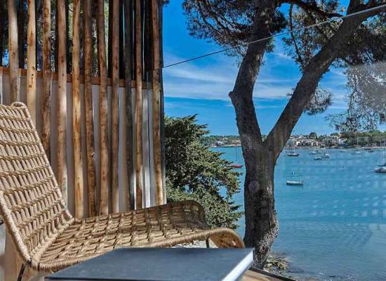 Terrasse mit Ausblick auf das Meer, Holzmöbel und mediterrane Landschaft im Barefoot Hotel Mallorca.
