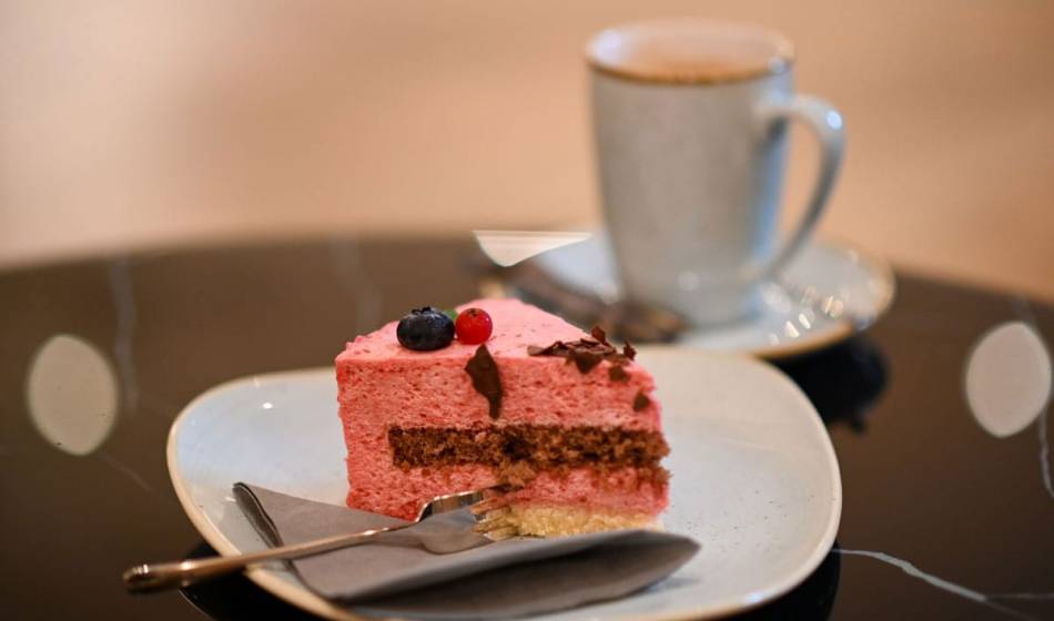 Delicious cake with fresh berries and a cup of coffee in the cozy lounge living room of the Vju Hotel on Rügen.