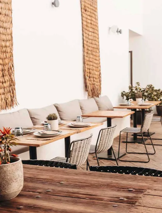 Blick in das moderne Barefoot Restaurant mit hellen Sesseln, Holzdekor und eingedeckten Tischen im Barefoot Hotel auf Mallorca.