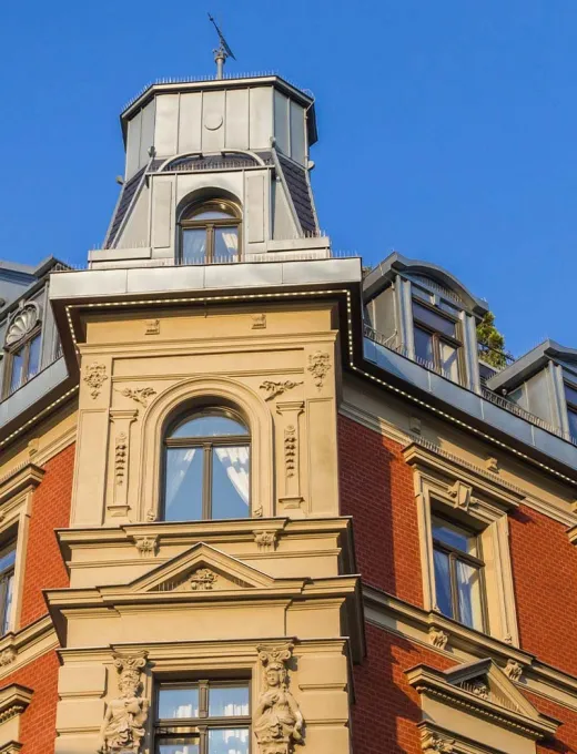 Detailed shot of a historic facade with decorated elements and towers under a blue sky.