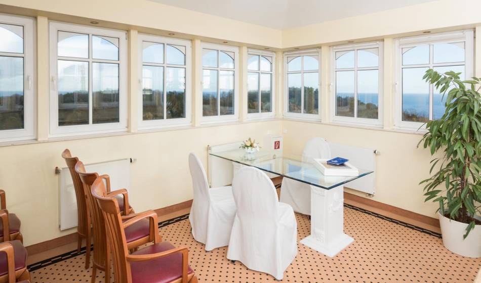 Room for wedding ceremonies in the Vju Hotel on Rügen, table and chairs in a bright environment, large windows with a view.