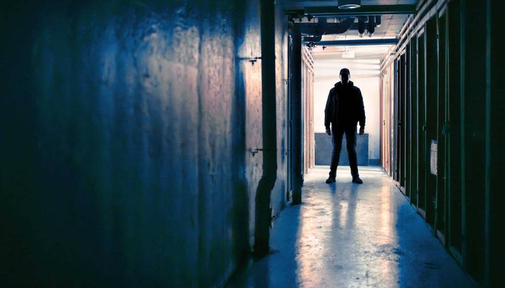 Ein dunkel gekleideter Mann steht in einem dunklen Tunnel.