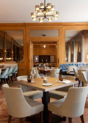 Blick durch ein Weinregal in das elegante Restaurant AnnA mit gedeckten Tischen.